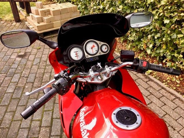 Ein rotes Kawasaki-Motorrad ist auf einem gemauerten Bürgersteig geparkt