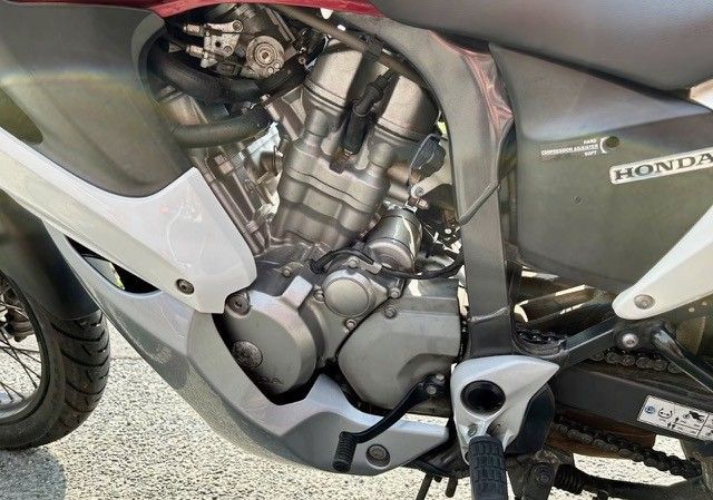 Hinter den weißen und grauen Karosserieteilen ist ein Motorradmotor mit silbernen und grauen Komponenten zu sehen. Der Motor ist teilweise freigelegt.