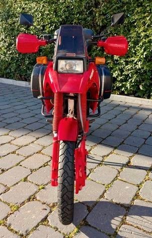 Auf einer gepflasterten Auffahrt ist ein rotes Motorrad geparkt.