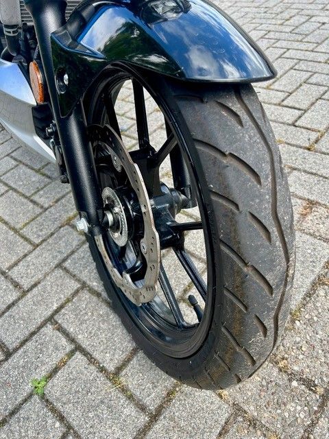 Nahaufnahme eines Motorradvorderrads und -reifens auf einer mit Ziegeln gepflasterten Straße