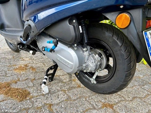 Eine Nahaufnahme des Hinterrads eines Motorrollers auf einer Ziegelsteinstraße.