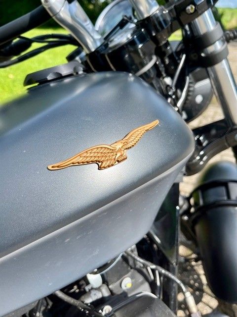 Mattgrauer Motorrad-Benzintank mit bronzenem Adler-Emblem.