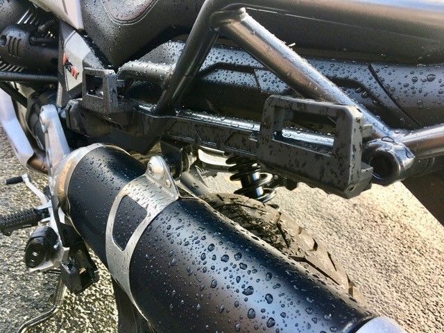 Eine Nahaufnahme eines Motorradauspuffs mit Wassertropfen darauf.