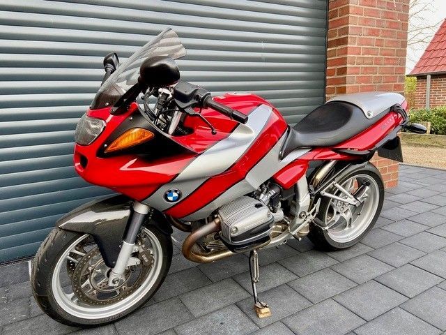 Ein rot-silbernes Motorrad steht vor einem Garagentor