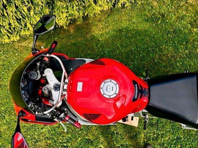 Rot-schwarzes Sportmotorrad von oben auf grünem Gras betrachtet.