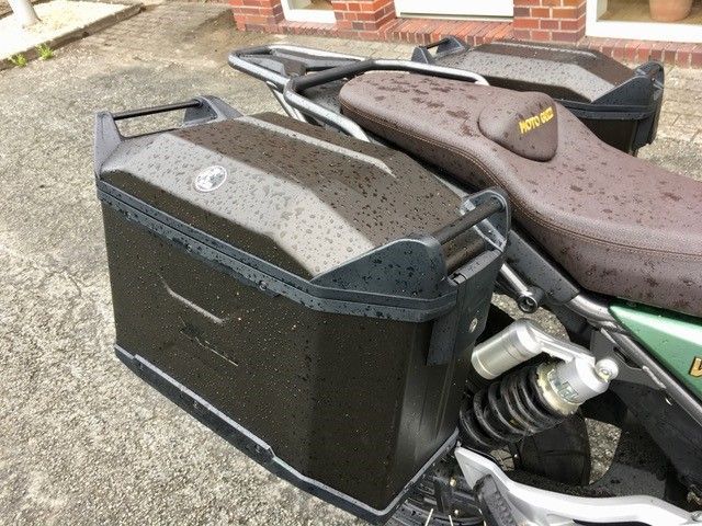 Vor einem Backsteingebäude ist ein Motorrad geparkt.