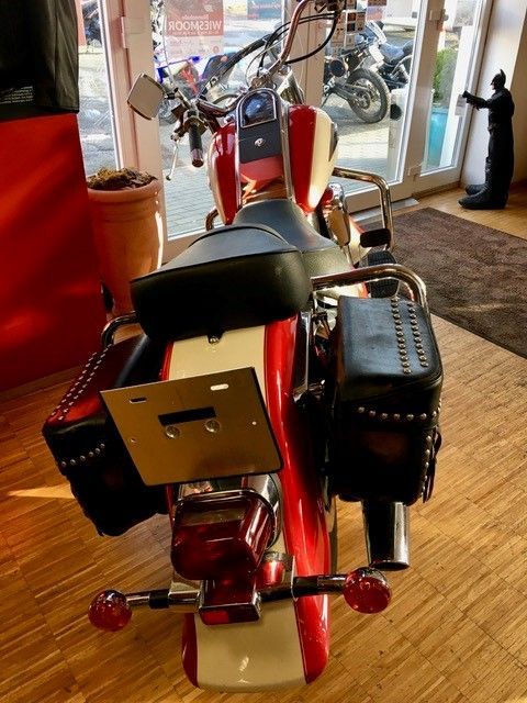 Ein rot-weißes Motorrad steht in einem Ausstellungsraum