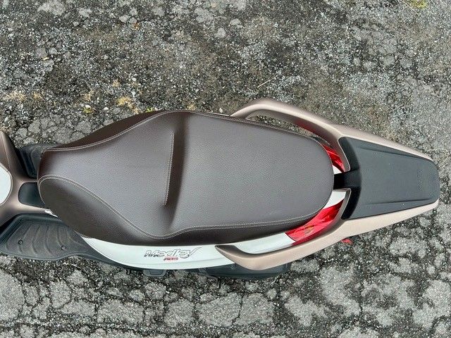 Draufsicht auf einen braun-schwarzen Motorradsitz auf rissigem Asphalt