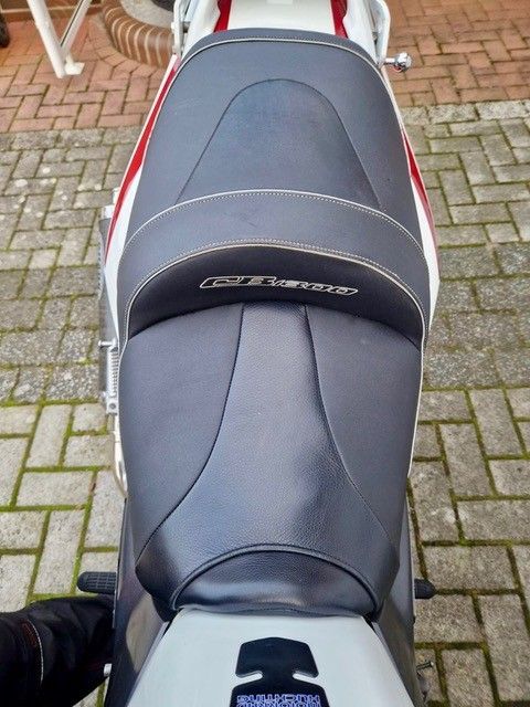 Motorradsitz, weiß mit schwarzem Kissen, GT Turbo-Logo, roter Streifen, ziegelfarbener Hintergrund.