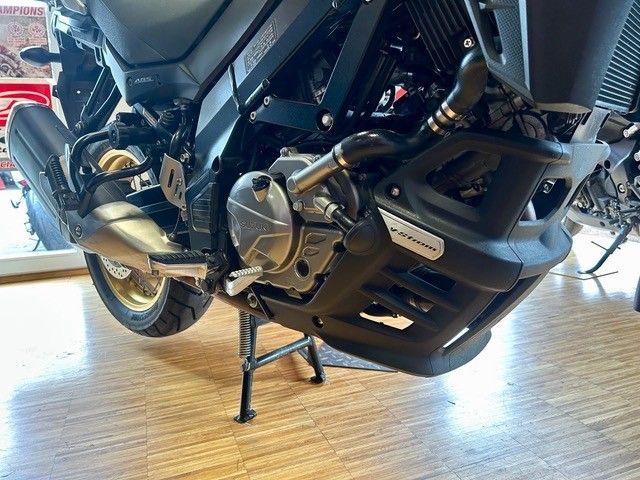 Schwarzes Motorrad, das in einem Ausstellungsraum in einer Halle geparkt ist, Seitenansicht mit ausgeklapptem Ständer.