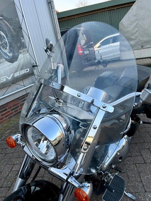 Vor einem Gebäude parkt ein Motorrad mit Windschutzscheibe.