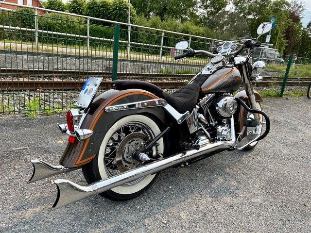 Ein Motorrad der Marke Harley Davidson steht auf einem Parkplatz neben den Bahngleisen.