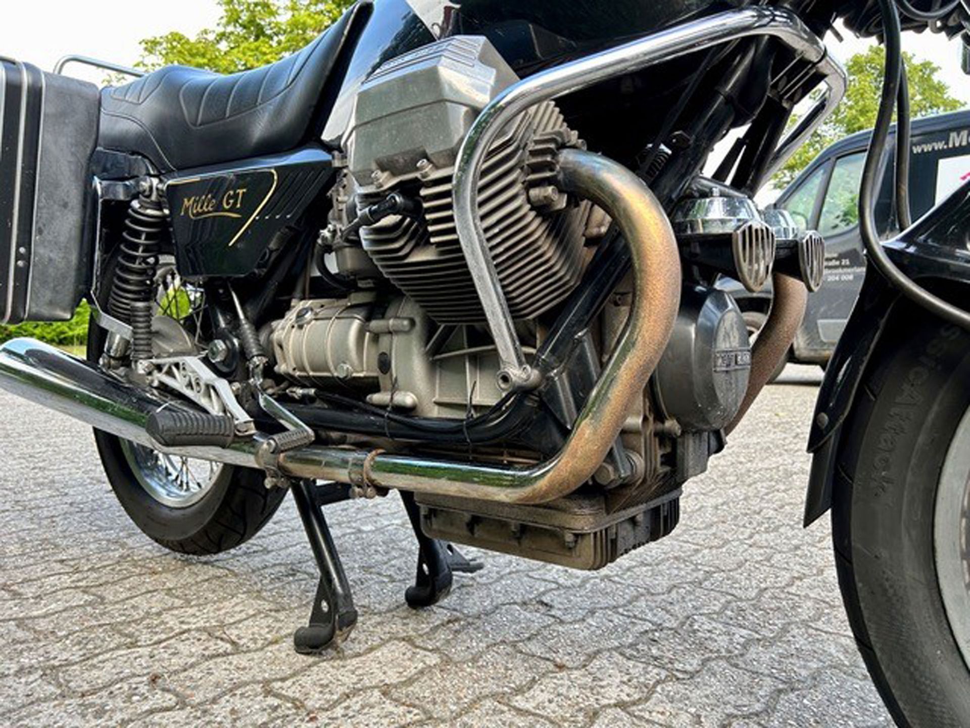 Schwarzes Moto Guzzi-Motorrad, auf einer Ziegelfläche geparkt, Nahaufnahme des Motors und der Seite.