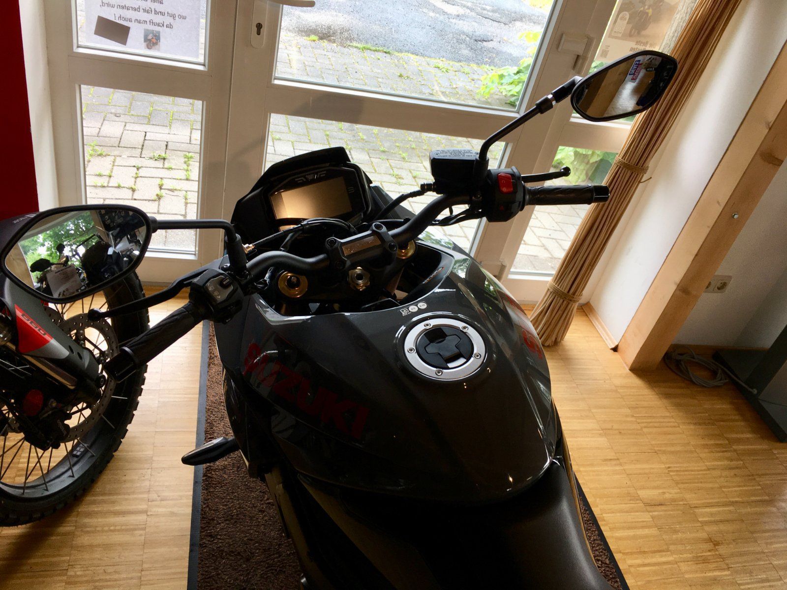 Ein schwarzes Motorrad ist in einem Raum neben einem Fenster geparkt.