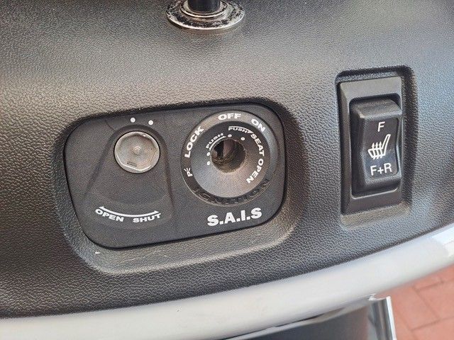 Armaturenbrett mit Zündschlüssel, Sitzheizungsschalter und Ablagefach. Schwarzer Kunststoff mit silbernen Akzenten.