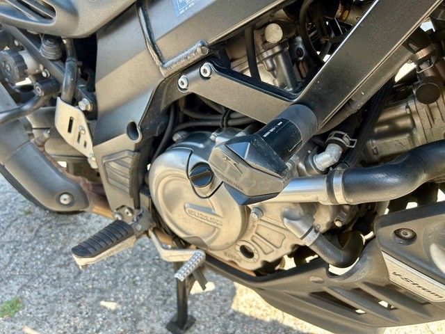 Nahaufnahme eines Motorradmotors und der Fußrasten auf einer gepflasterten Oberfläche
