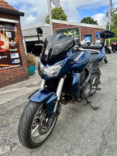 Ein blaues Sportmotorrad parkte vor einem Backsteingebäude in einer Straße.