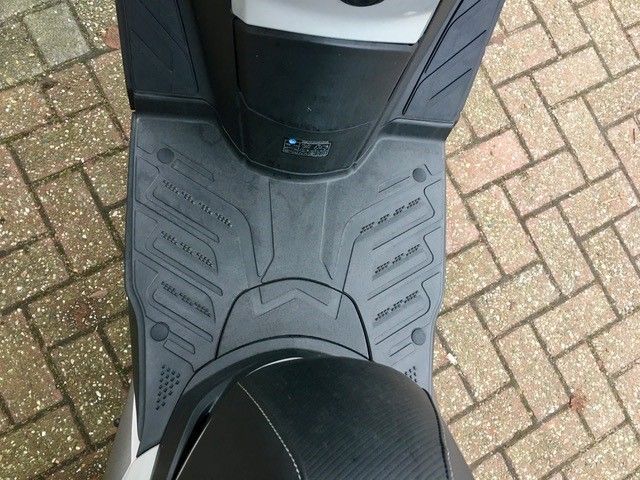 Ein schwarz-weißer Roller ist auf einem gemauerten Bürgersteig geparkt