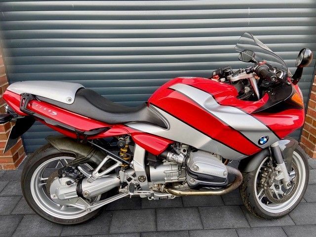 Ein rot-silbernes Motorrad steht vor einem Garagentor