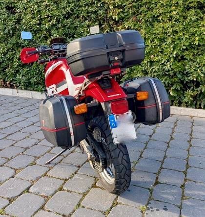 Ein rotes Motorrad ist auf einer gemauerten Auffahrt geparkt