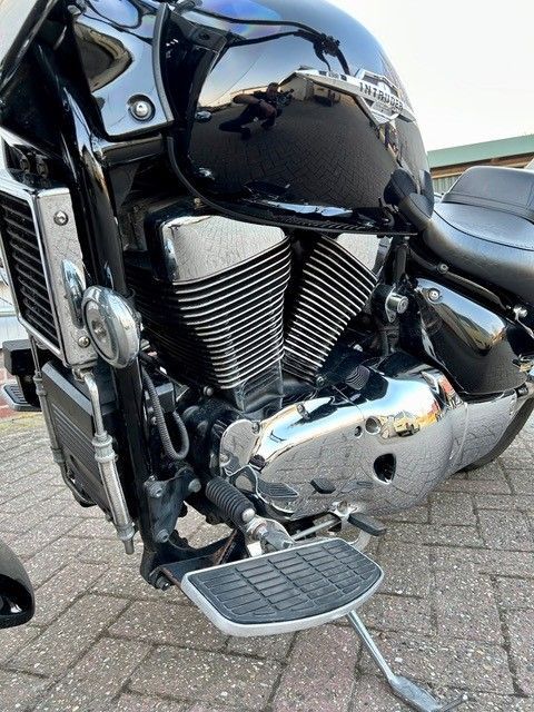 Auf einer gepflasterten Straße ist ein schwarzes Motorrad geparkt.