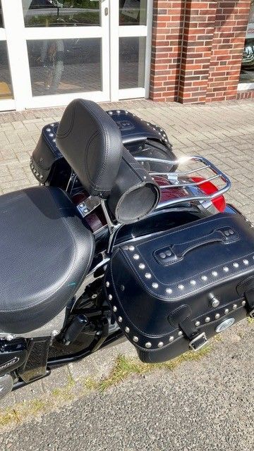 Ein schwarzes Motorrad ist am Straßenrand vor einem Backsteingebäude geparkt.