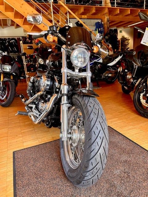 Schwarzes Motorrad, Frontansicht in einem Ausstellungsraum, mit Chromdetails und einem großen Reifen auf einer Matte.