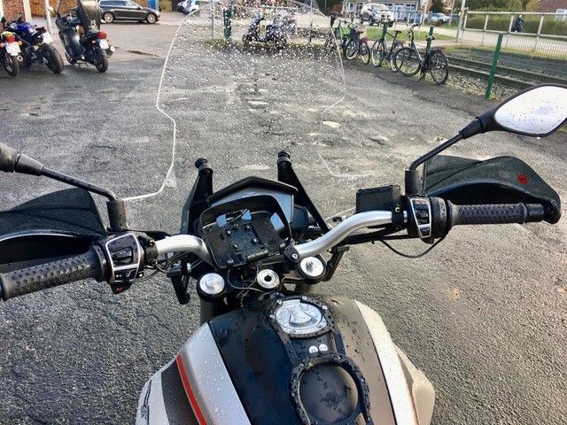 Auf einem Parkplatz steht ein Motorrad am Straßenrand.