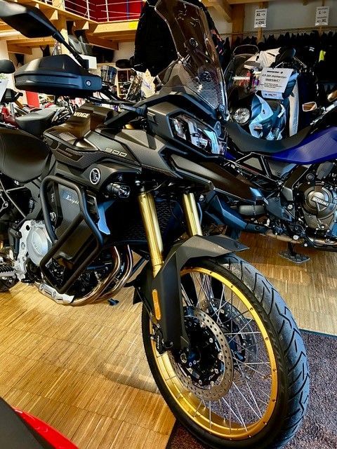 Auf einem Holzboden ist ein schwarz-goldenes Motorrad geparkt.