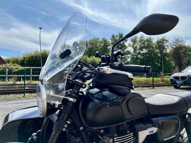 Motorrad mit Windschutzscheibe, schwarze Karosserie, an einem sonnigen Tag im Freien geparkt.