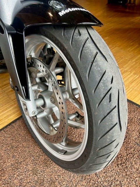 Nahaufnahme eines Motorradvorderrads mit Scheibenbremse auf einem Holzboden