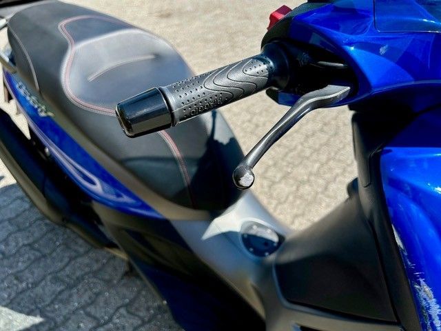 Ein blauer Roller ist auf einem gemauerten Bürgersteig geparkt