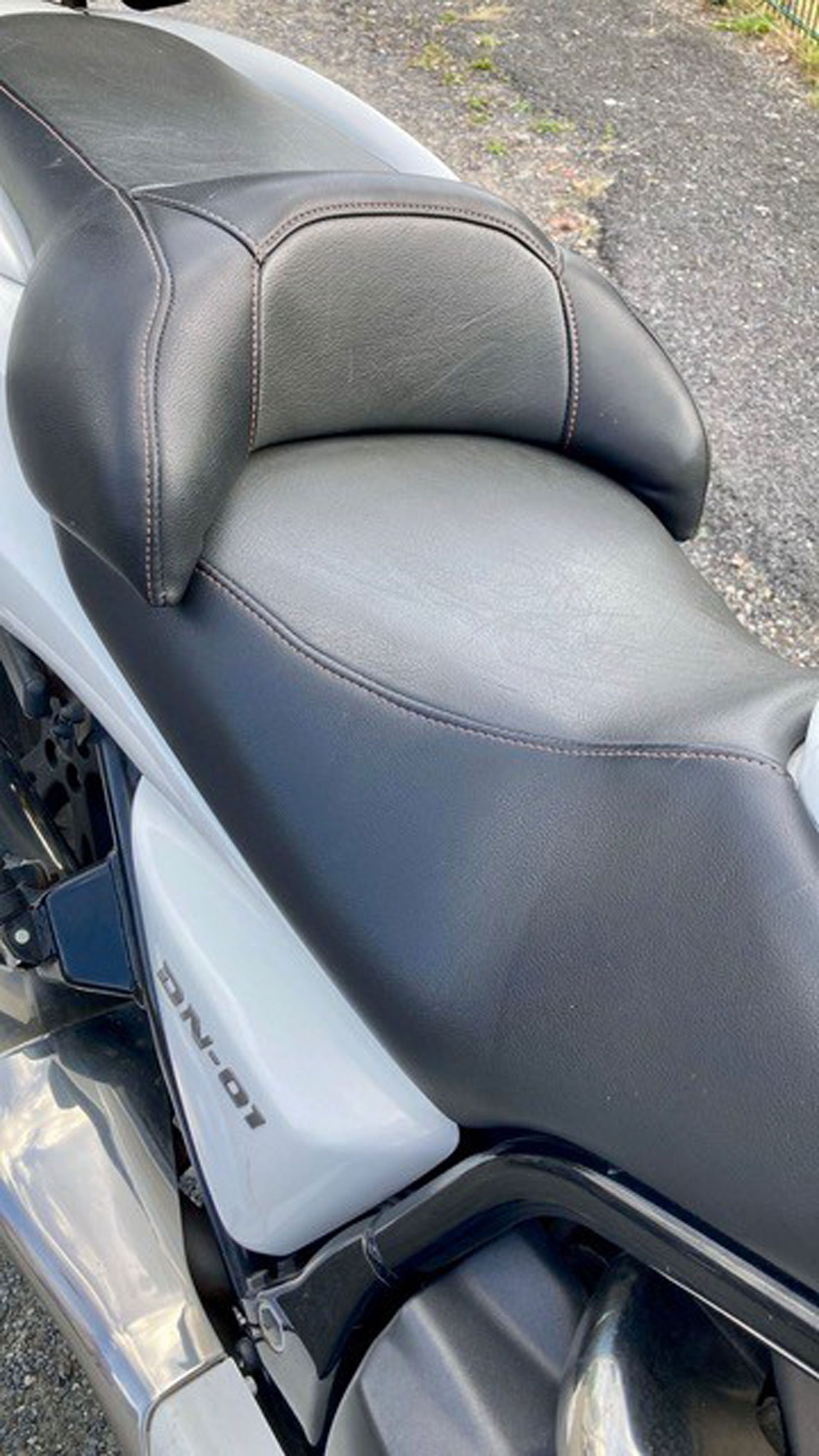 Schwarzer Motorradsitz mit Rückenlehne.