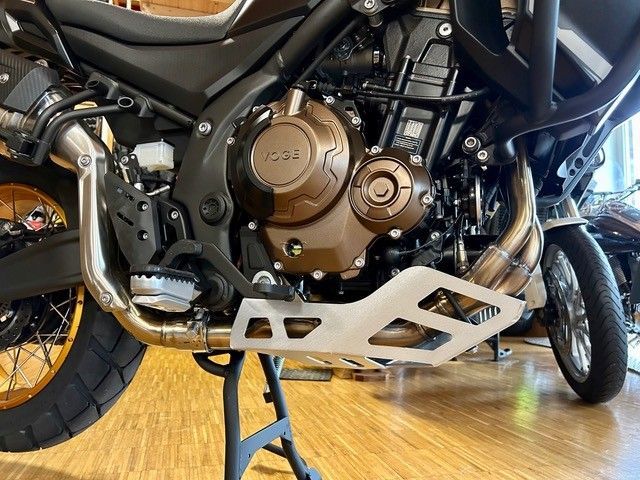 Ein Motorradmotor steht auf einem Holzboden.