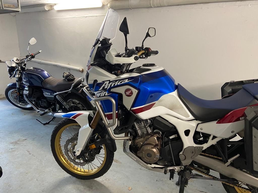 Zwei Motorräder sind nebeneinander in einer Garage geparkt.