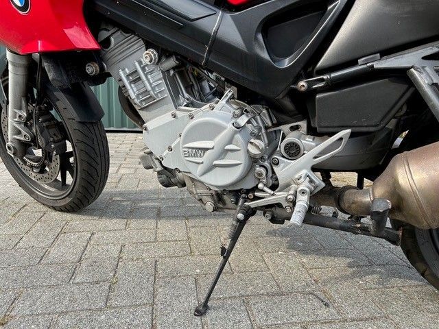 Ein rotes BMW-Motorrad ist auf einem gemauerten Bürgersteig geparkt