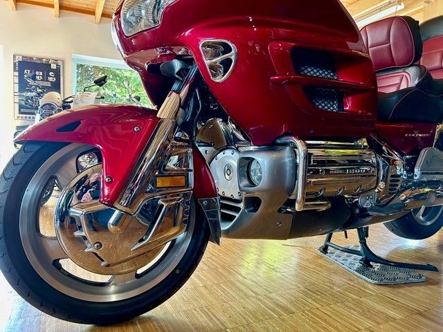 Nahaufnahme eines glänzend roten Honda Goldwing-Motorrads mit Vorderrad, Chromdetails und Verkleidung.