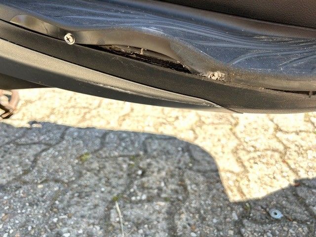 Eine Nahaufnahme der Stoßstange eines Motorrads auf einem gepflasterten Gehweg.