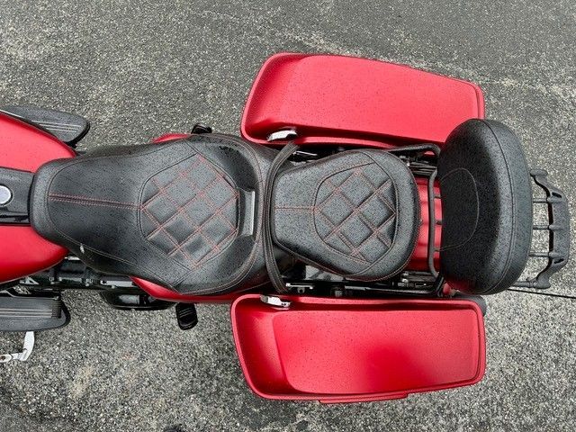 Draufsicht auf ein rotes Motorrad mit schwarzem Sitz und Seitenkoffern auf dem Asphalt