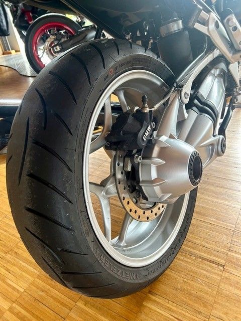 Nahaufnahme eines Motorradhinterrads mit Scheibenbremse auf einem Holzboden.