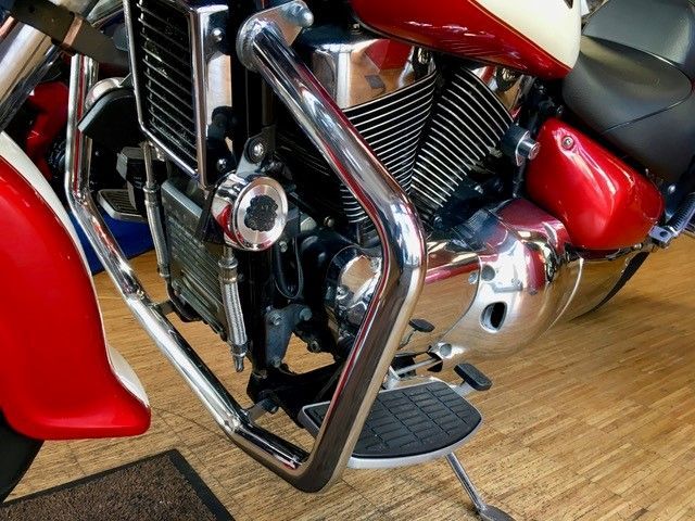 Ein rot-weißes Motorrad ist auf einem Holzboden geparkt