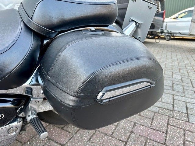 Auf einer gepflasterten Straße ist ein schwarzes Motorrad geparkt.