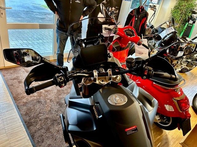 Ein Mann steht in einem Ausstellungsraum neben einem Motorrad.