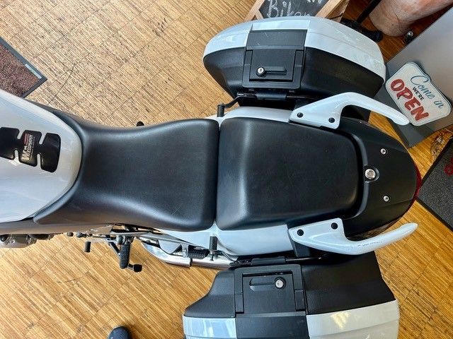 Draufsicht auf einen schwarzen Motorradsitz und hintere Staukästen auf einem Holzboden