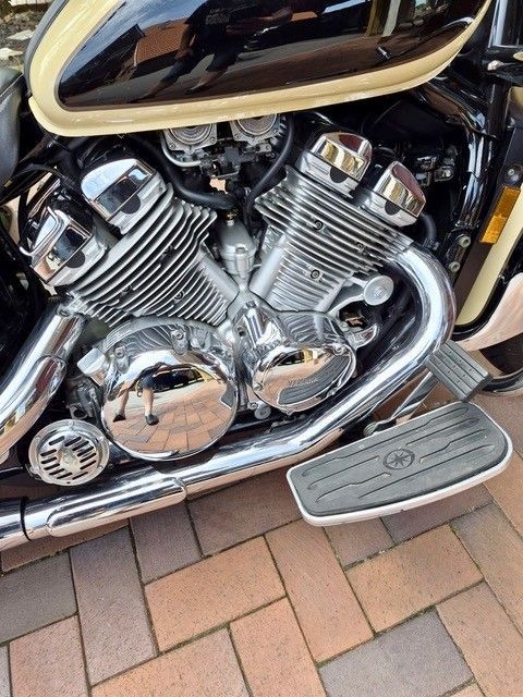 Verchromter Motorradmotor mit schwarz-goldener Karosserie, Nahaufnahme über Backsteinpflaster.