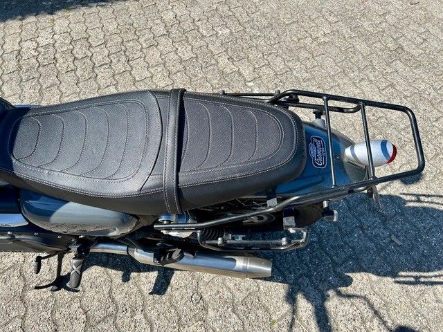 Auf einer gepflasterten Straße ist ein schwarzes Motorrad geparkt.