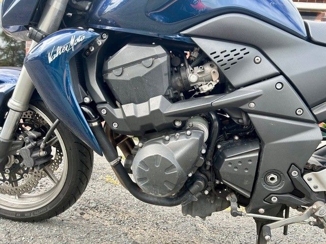 Blaues Sportmotorrad auf Schotter geparkt, Seitenansicht mit Blick auf Motor und Vorderrad
