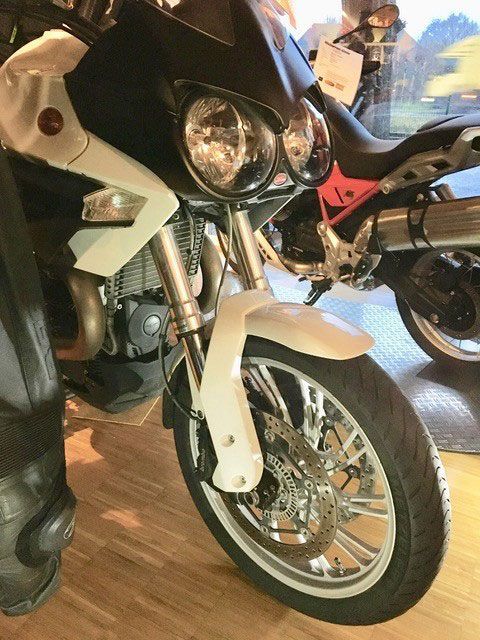 Ein schwarz-weißes Motorrad ist auf einem Holzboden geparkt