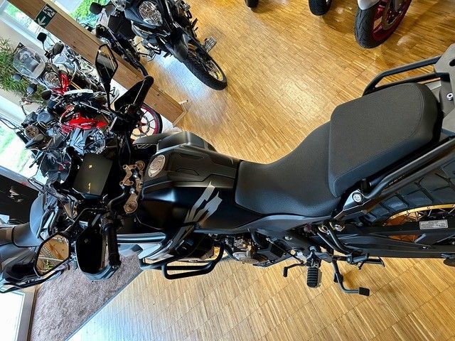 Ein schwarzes Motorrad steht auf einem Holzboden in einem Ausstellungsraum.