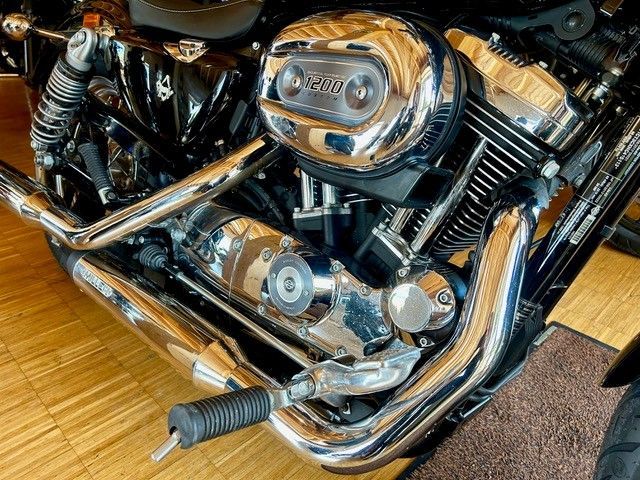 Nahaufnahme eines verchromten Motorradmotors und Auspuffrohren auf einem Holzboden